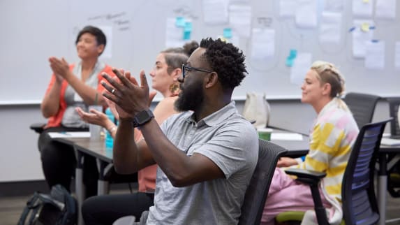 4 people inside a classroom clapping